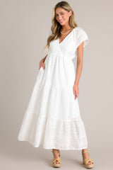 White maxi dress with v-neckline, removable slip, thin elastic waistband, hip pockets, eyelet detailing, and faux pearl trimmed sleeves.