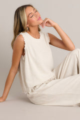 This sandstone tank features a crew neckline, functional buttons down the back, frayed shoulders, and a frayed hemline.