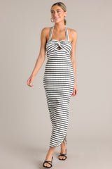 Angled full body view of this stripe maxi dress that features a self-tie halter neckline, twist detailing in the bust, a chest cutout, an open back, a textured material, and a side slit.