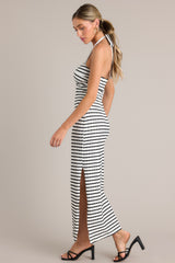 Side view of this stripe maxi dress that features a self-tie halter neckline, twist detailing in the bust, a chest cutout, an open back, a textured material, and a side slit.