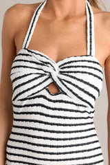 Close up view of this stripe maxi dress that features a self-tie halter neckline, twist detailing in the bust, a chest cutout, an open back, a textured material, and a side slit.