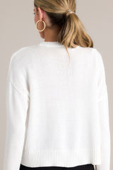 Back view of this white sweater that features a ribbed crew neckline, embroidered wording, a soft knitted fabric, and a ribbed hemline.