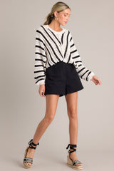 Full body view of an ecru and black sweater featuring a ribbed crew neckline, long sleeves with ribbed cuffs, a bottom ribbed hem that tapers in, and a chunky knit design throughout.