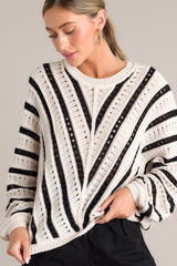 Front view of an ecru and black sweater featuring a ribbed crew neckline, long sleeves with ribbed cuffs, a bottom ribbed hem that tapers in, and a chunky knit design throughout.