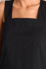 Close up view of this black tank that features a square neckline, thick straps that cross in the back, a relaxed fit, and an open lower back design.