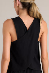 Back view of this black tank that features a square neckline, thick straps that cross in the back, a relaxed fit, and an open lower back design.