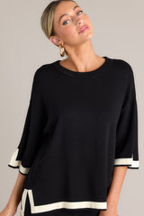 Angled front view of this black sweater top that features a crew neckline, a relaxed fit, split quarter sleeves, and contrasting split hemlines.