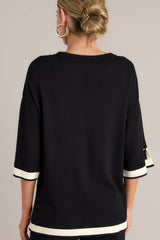 Back view of this black sweater top that features a crew neckline, a relaxed fit, split quarter sleeves, and contrasting split hemlines.