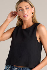 Front view of this black top that features a crew neckline, a keyhole cutout with a functional button, and a back slit.