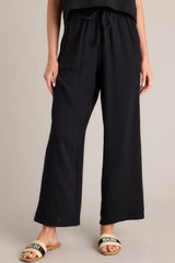These black pants feature a high waisted design, an elastic waistband, a self-tie drawstring, functional hip pockets, and a wide leg.