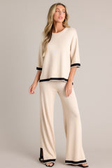 Angled full body view of this beige sweater top that features a crew neckline, a relaxed fit, split quarter sleeves, and contrasting split hemlines.