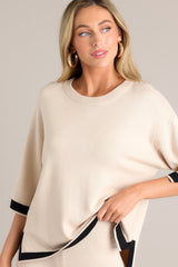 This beige sweater top features a crew neckline, a relaxed fit, split quarter sleeves, and contrasting split hemlines.