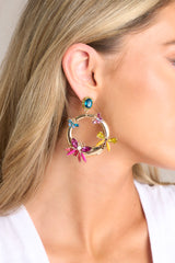 These earrings feature gold hardware, a rhinestone stud connected to a hoop design, colored butterfly shaped rhinestone details, and secure post backings.
