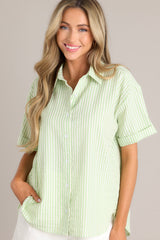 Front view of this light green top with collared neckline, front buttons, cuffed short sleeves, single pleat detail in back.
