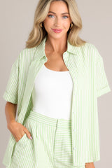 Close up front view of this light green top with collared neckline, front buttons, cuffed short sleeves, single pleat detail in back.