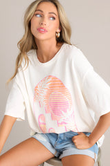 Angled close up view of this tee with crew neckline, summer-themed graphic, oversized fit, wide half sleeves.