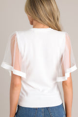 Back view of this white top that features a crew neckline, a soft stretchy fabric, and sheer short butterfly sleeves.