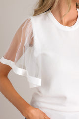 Close up view of this white top featuring sheer short butterfly sleeves.