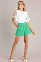 Front view of these kelly green shorts that feature functional pockets and pleated details. 