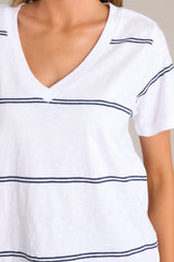 Close up view of his white tee that features a v-neckline, a soft lightweight fabric, and a twin stripe pattern.