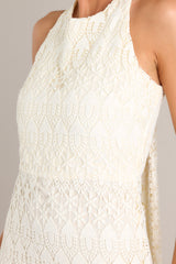 Close up view of this dress that features a halter neckline with a self-tie in the back, a cutout detail in the back with hook and eye closures, a zipper up the back, and a lining that extends from the neckline to the upper thigh.