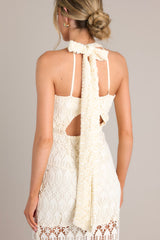 Back view of this dress that features a halter neckline with a self-tie in the back, a cutout detail in the back with hook and eye closures, a zipper up the back, and a lining that extends from the neckline to the upper thigh.