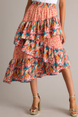 This multi-colored skirt features an elastic waistband, tiered ruffles, colorful prints, and an asymmetrical hem.