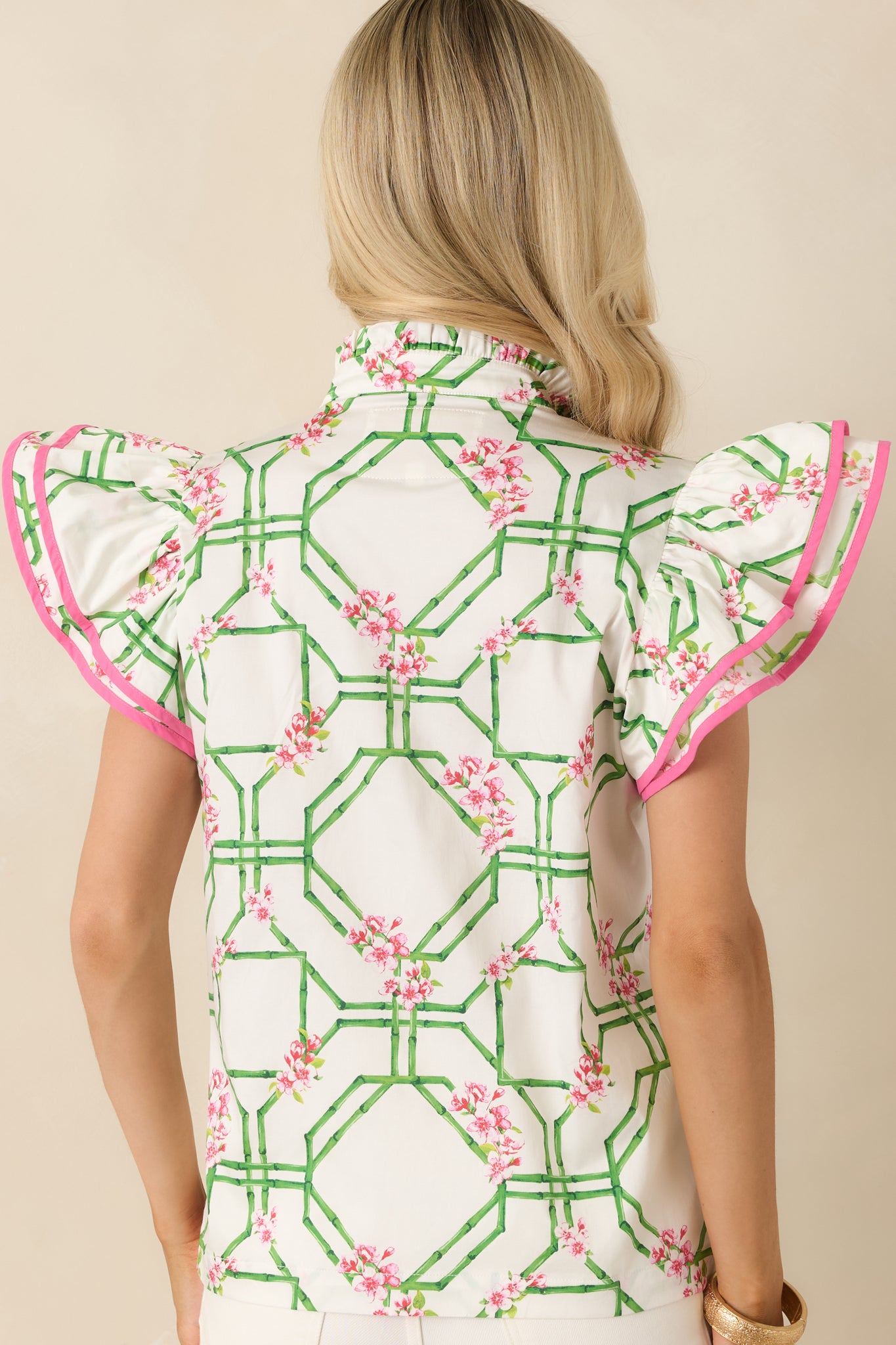 Rear view of the white cotton blouse featuring a smooth woven finish and flutter sleeve silhouette.