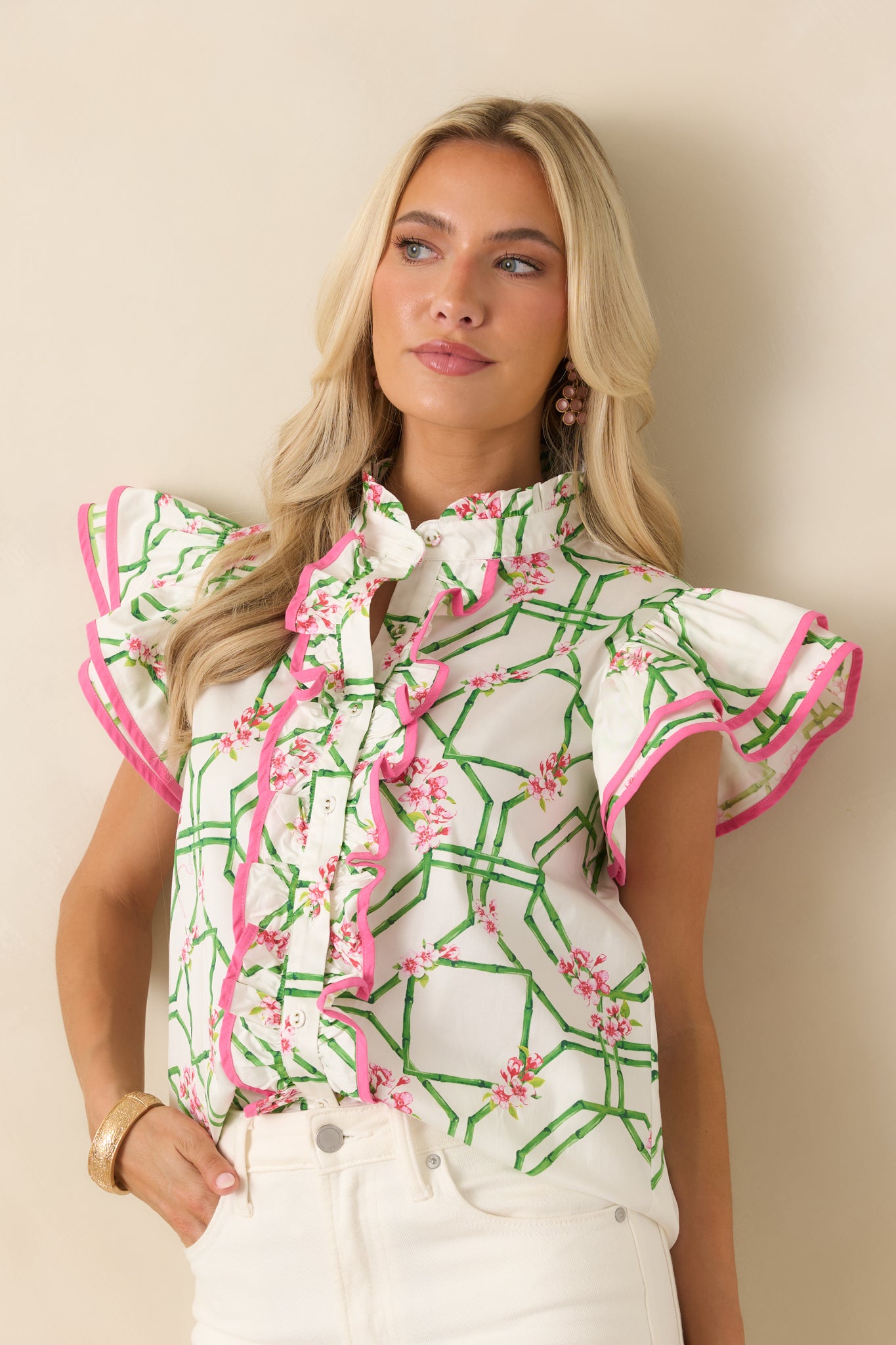 White floral top featuring a high neckline and ruffle-trimmed button placket in a lightweight woven finish.