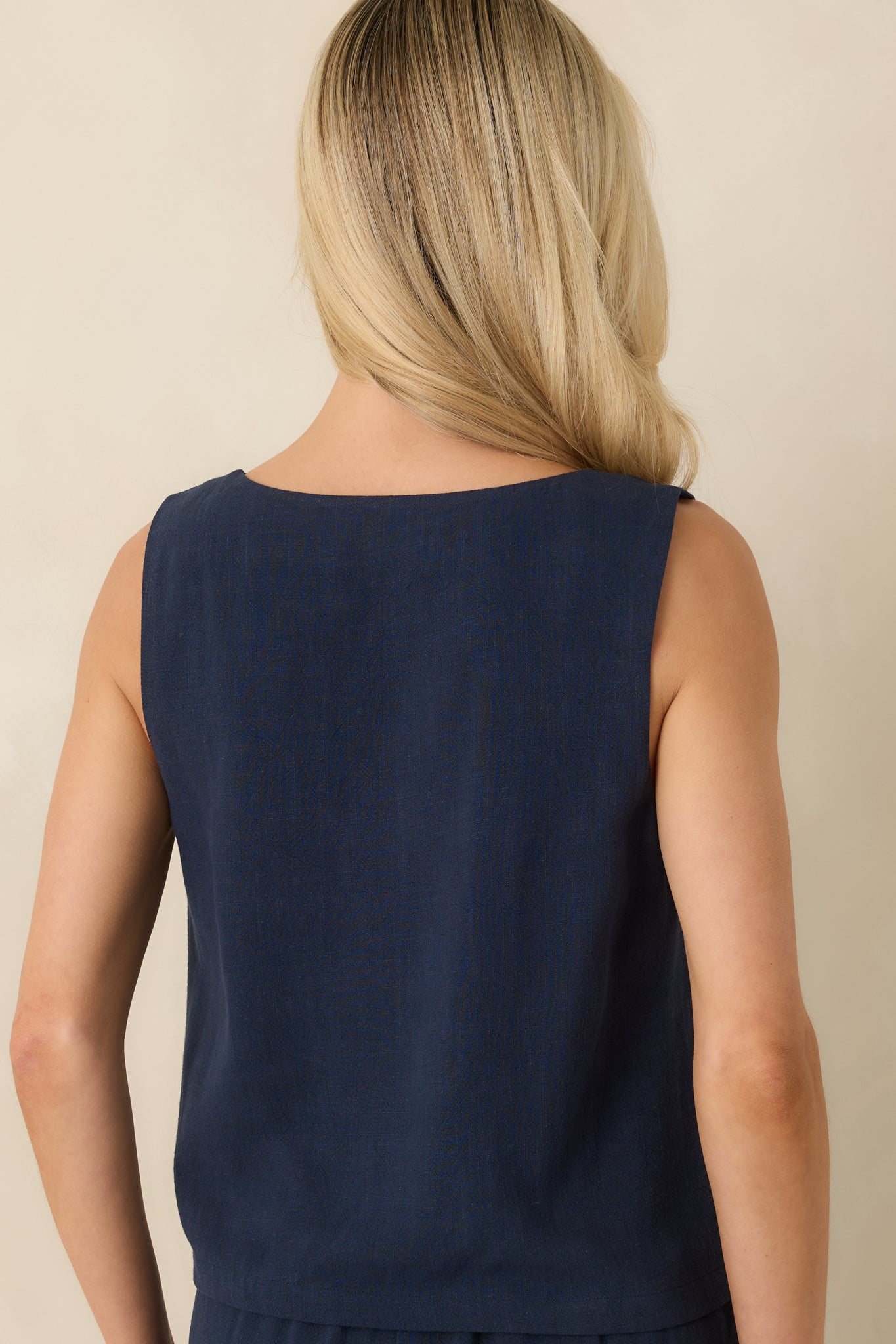 Rear view of the navy cropped tank highlighting the clean back finish, sleeveless cut, and relaxed drape through the lightweight fabric.


