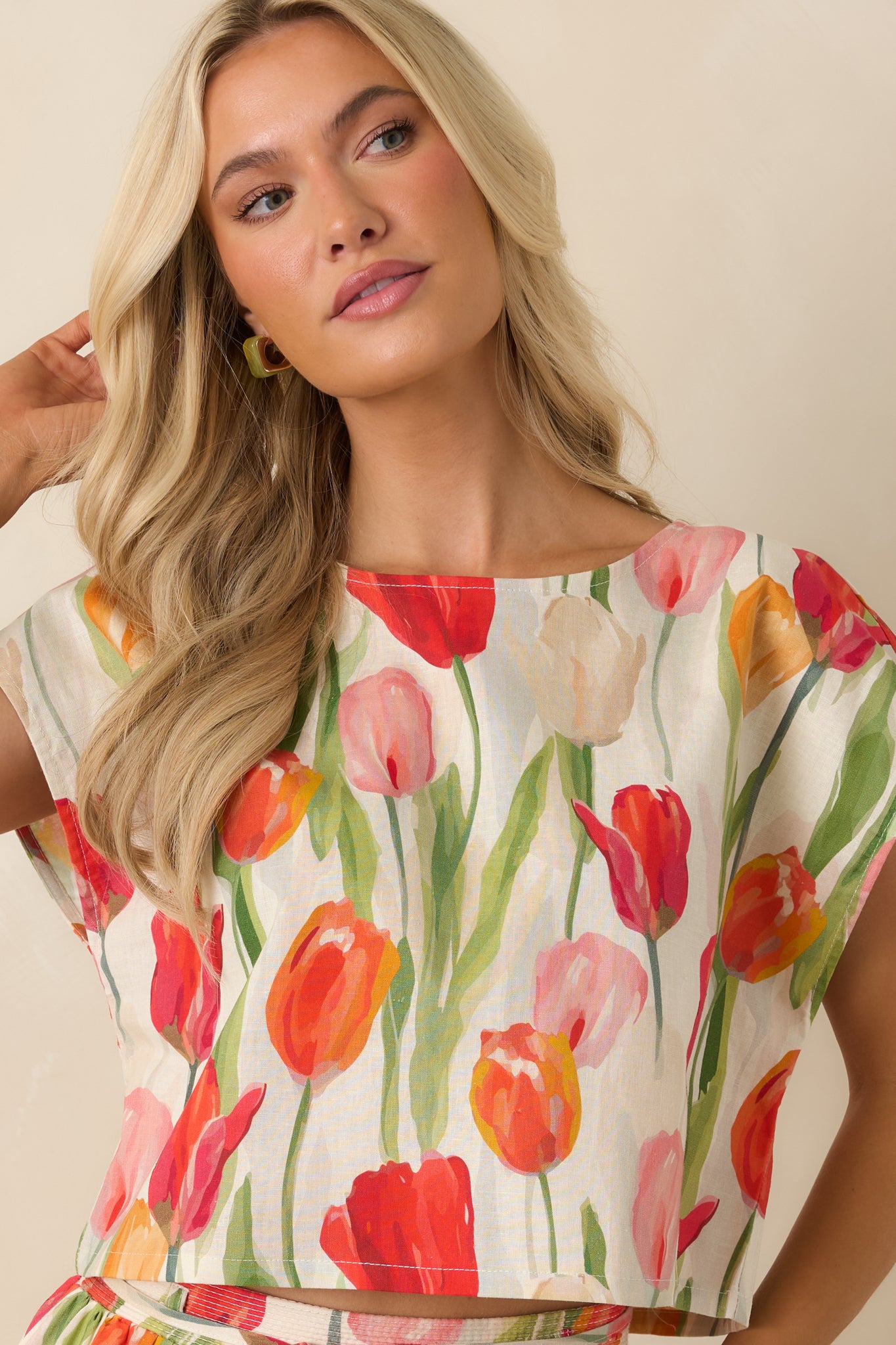 Close view of the ivory floral cropped top highlighting the colorful tulip print and relaxed cap-style sleeves.