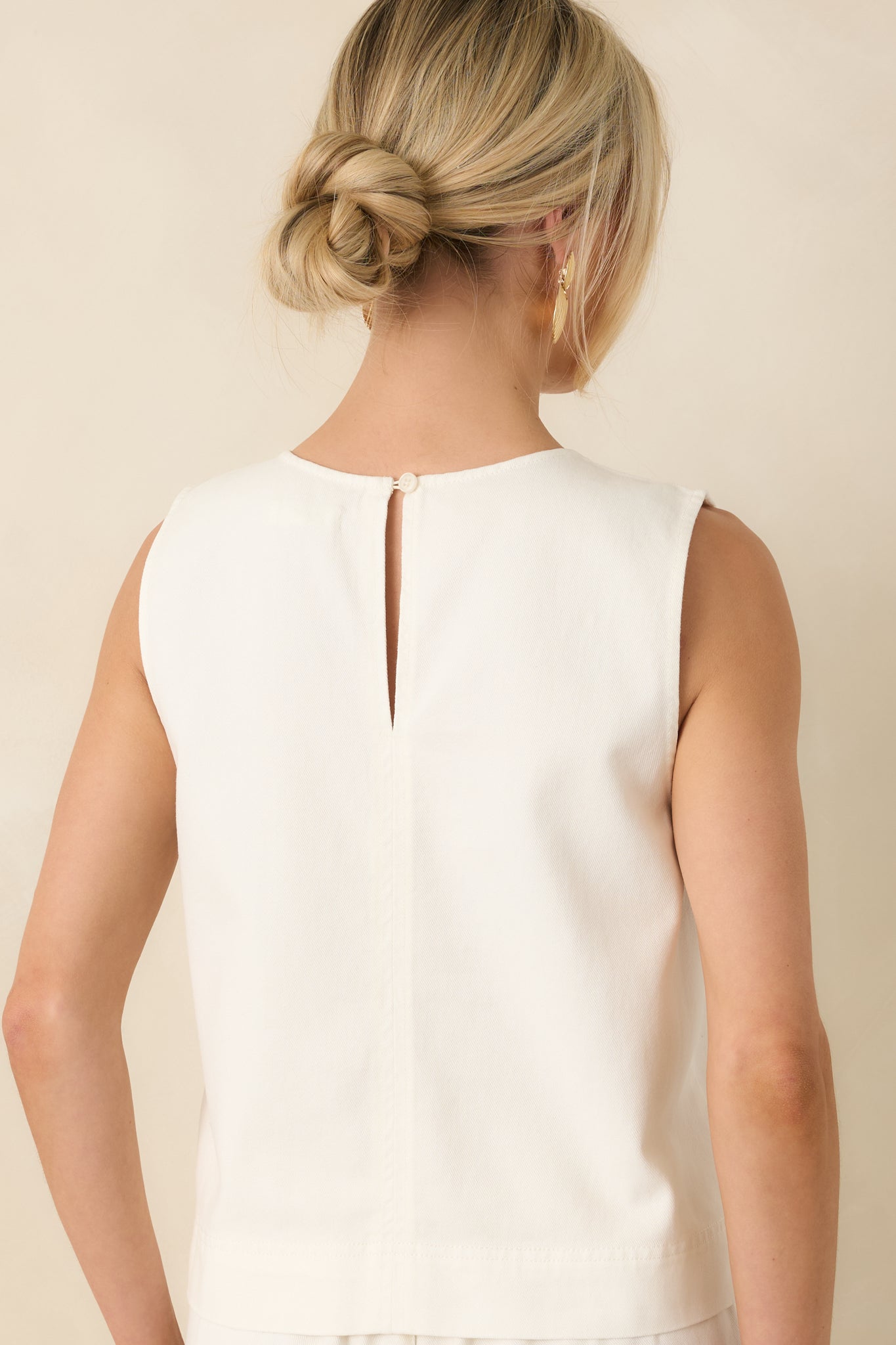 Rear view of the ivory cropped tank featuring a back keyhole button closure and clean, minimal finish with relaxed drape.

