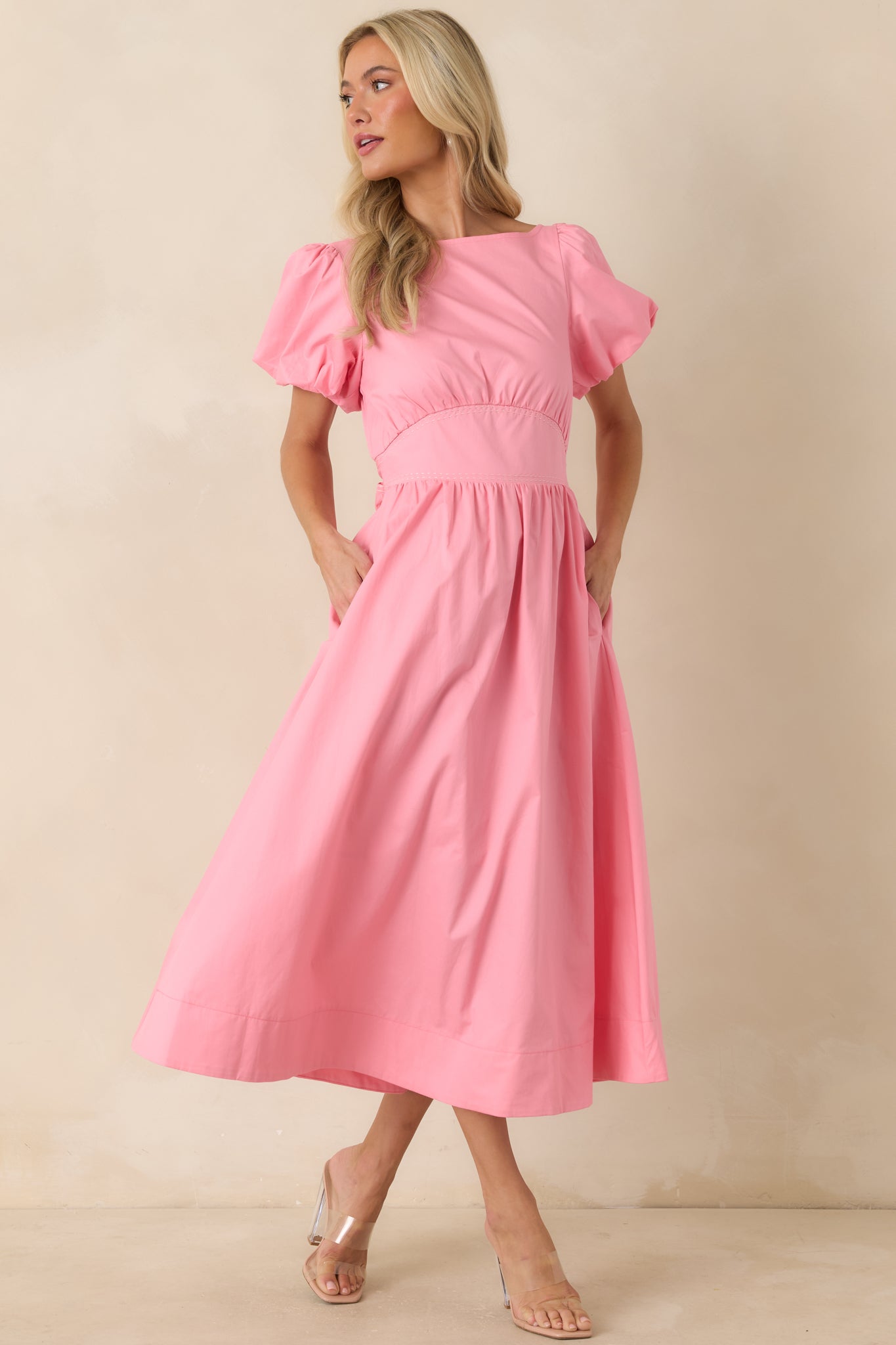 Feminine pink midi dress designed with elastic cuffed sleeves, a defined empire waistband, and a relaxed skirt silhouette.