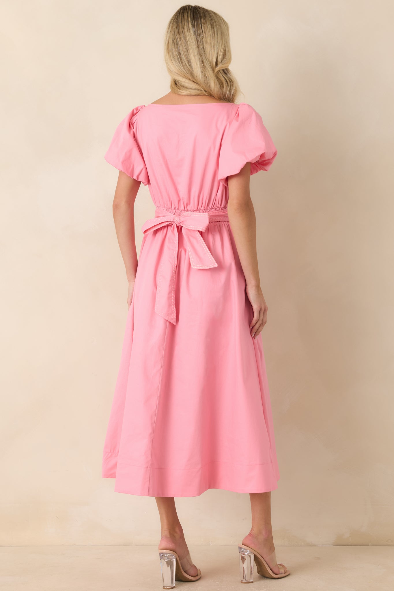 Back view of the pink cotton midi dress featuring puff sleeves, side zipper closure, and a flowing lined midi skirt.