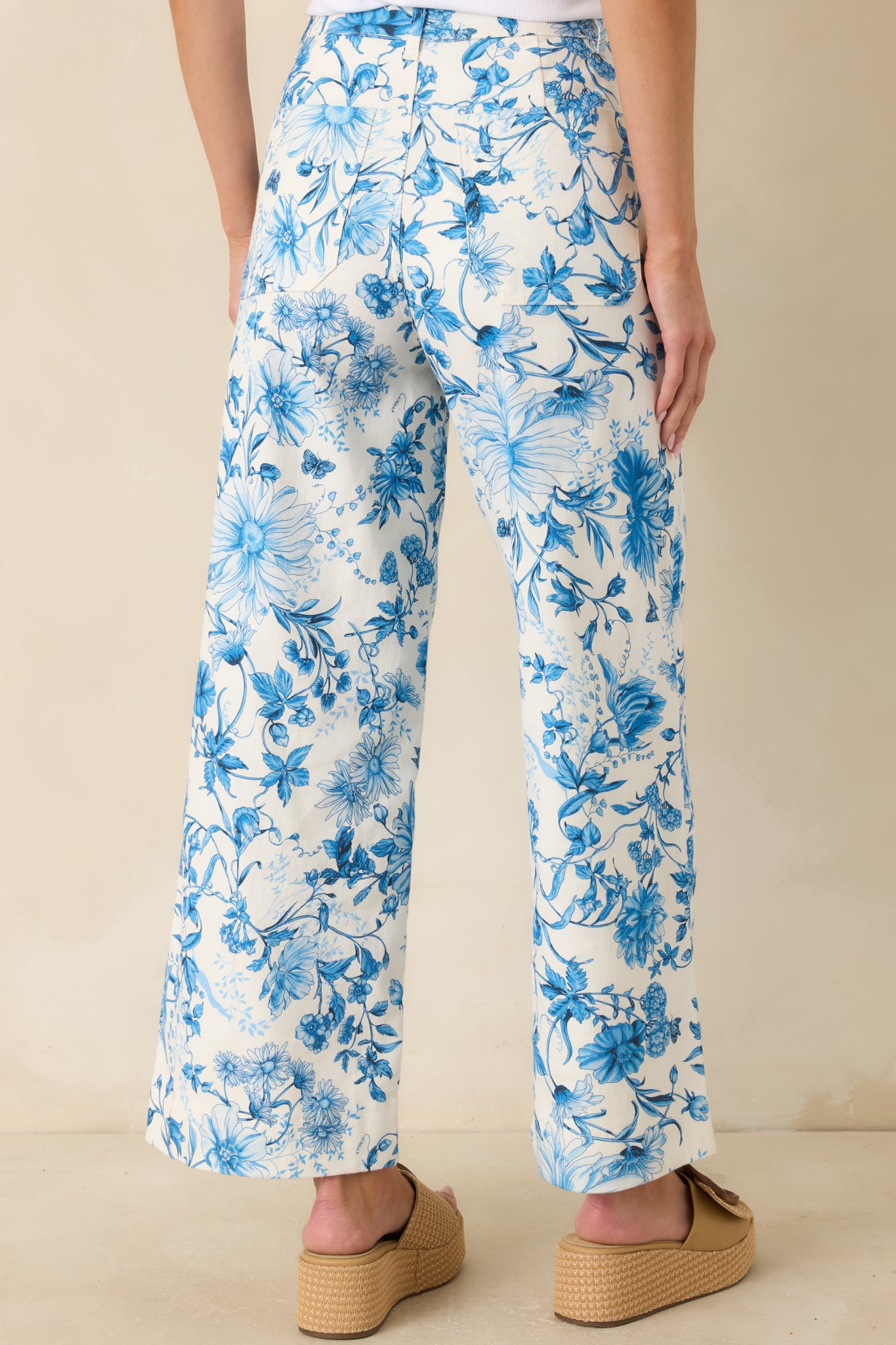 Rear view of blue floral pants with high-rise waist and straight wide leg silhouette.