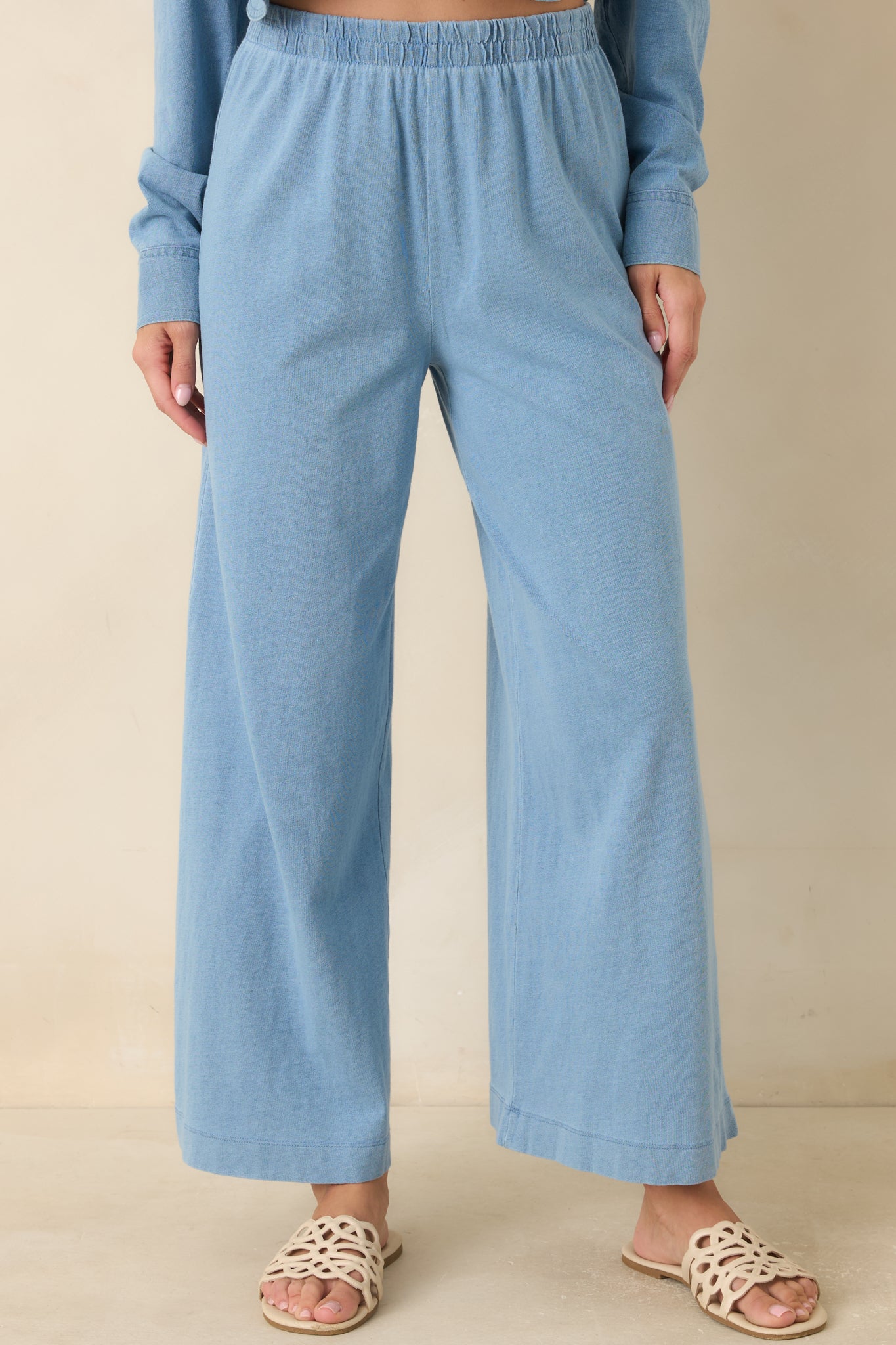 Detailed view of the high waisted elastic waistband on soft black jersey pants.