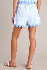 Back view of these light blue shorts that feature a high waisted design, an elastic waistband, functional hip pockets, and a thick ricrac hemline.