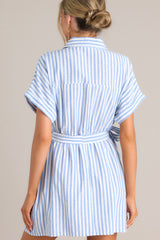 Back view of  this dress that features a collared v-neckline, a full button front, an elastic waistband, a self-tie belt, functional pockets, and folded sleeves.