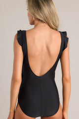 Back view of this black swimsuit that features a deep v-neckline, a shelf bra, removable padding, ruffled shoulders, a self-tie wrap style design, and an open back.