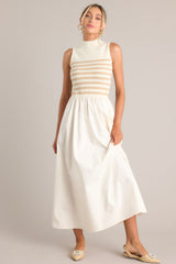 This tan and white dress features a high neckline, a striped sweater bodice, and a flowy skirt.