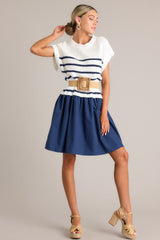 Angled full body view of this navy dress that features a crew neckline, a ribbed knitted bodice, horizontal stripes, and a solid flowy skirt.