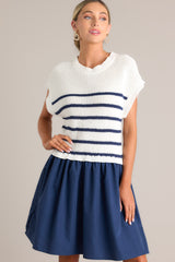 Front view of this navy dress that features a crew neckline, a ribbed knitted bodice, horizontal stripes, and a solid flowy skirt.