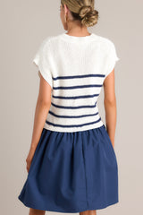Back view of this navy dress that features a crew neckline, a ribbed knitted bodice, horizontal stripes, and a solid flowy skirt.