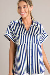 Front view of this top that features a collared neckline, a full button front, functional breast pockets, a satin-like material, wide cuffed sleeves, and a split hemline.