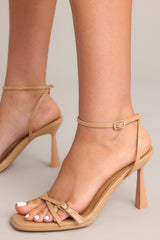 Side view of these tan shoes thatt feature a thin adjustable ankle strap, straps over the toes, and this heel.