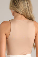 Back view of this camel bodysuit with high neckline, stretchy fabric, snap button closure, thong style bottom.