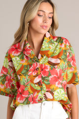 Angled close up front view of this coral tropical print top that features a collared neckline, fully functional buttons down the front, a citrus floral print design, and a slightly cropped fit.