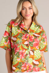 Front view of this coral tropical print top that features a collared neckline, fully functional buttons down the front, a citrus floral print design, and a slightly cropped fit.