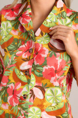 Close up view of this coral tropical print top that features a collared neckline, fully functional buttons down the front, a citrus floral print design, and a slightly cropped fit.