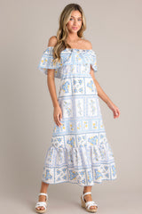 Angled front view of this white & blue maxi dress featuring an embroidered floral design, and a lined and tiered skirt.